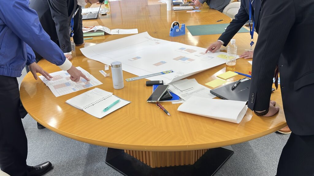選抜メンバーがテーブルに資料を広げて検討している様子